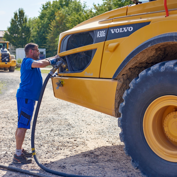 Mitarbeiter betankt einen großen gelben Volvo A30G Muldenkipper im Freien
